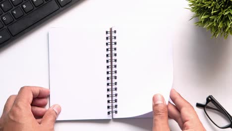 open notebook on a desk with hands and accessories