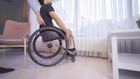 disabled youth in a wheelchair is walking around the house.