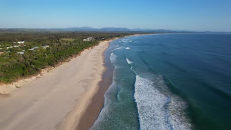 long stretch of sandy beach with waves splashing near brunswick river in new south wales, australia