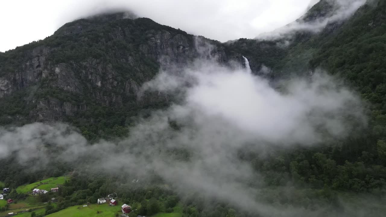 Norveç gölünün sonunda bulutlarla örtülü şelalenin drone videosu