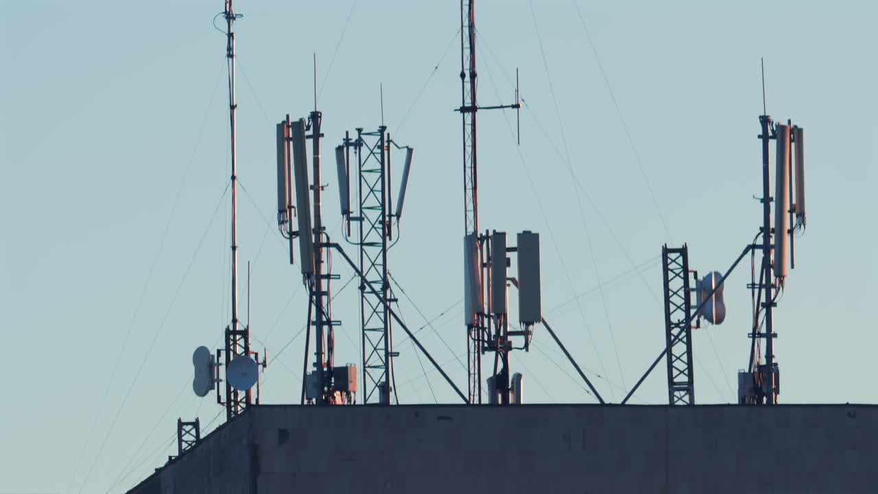 Antennas and communication towers stand on top of a building under the warm morning light