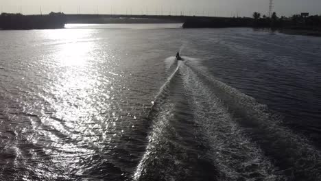 Drone footage of a jetsky traveling over the water. Sun is reflecting on the water.