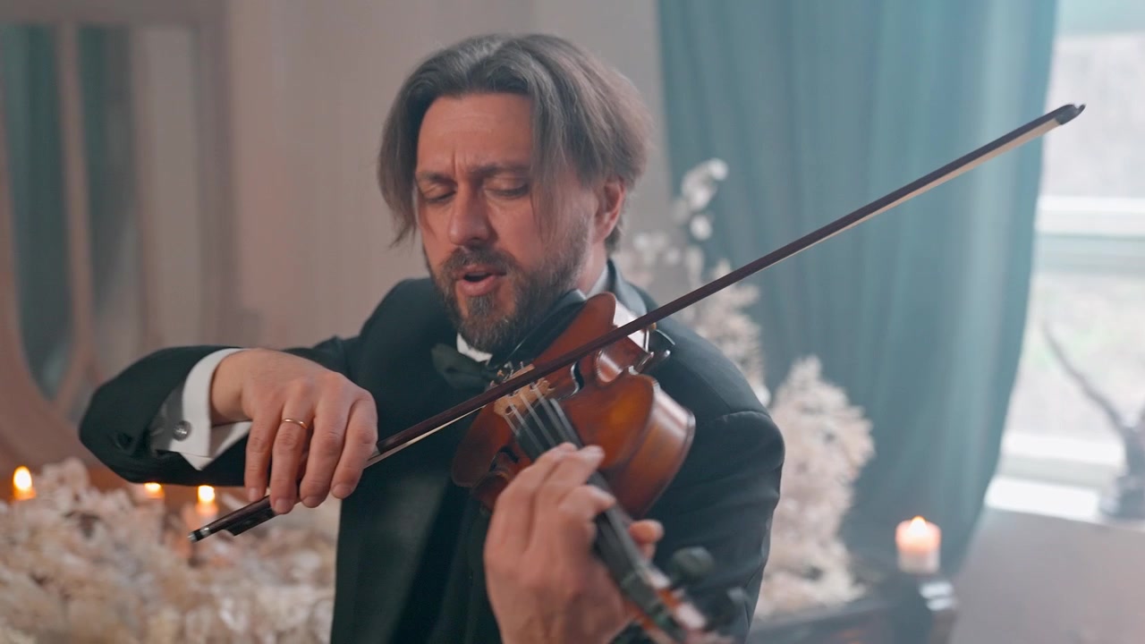 Uomo elegante in completo che suona il violino classico con concentrazione