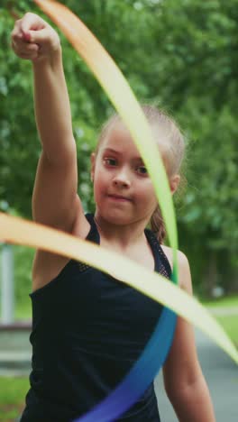 a young girl masterfully manipulates colorful ribbons in a joyous display of artistic expression amidst a lush green landscape