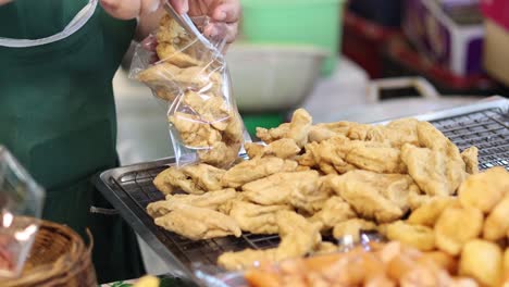 worker bags fish balls for sale at a market