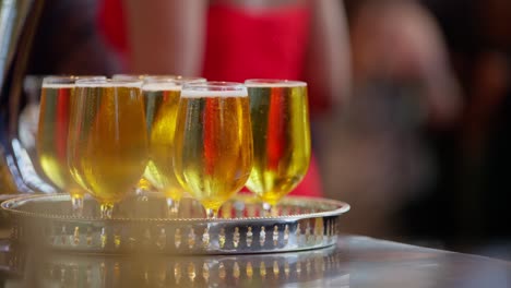 5 golden beers rest on a stainless steel serving tray