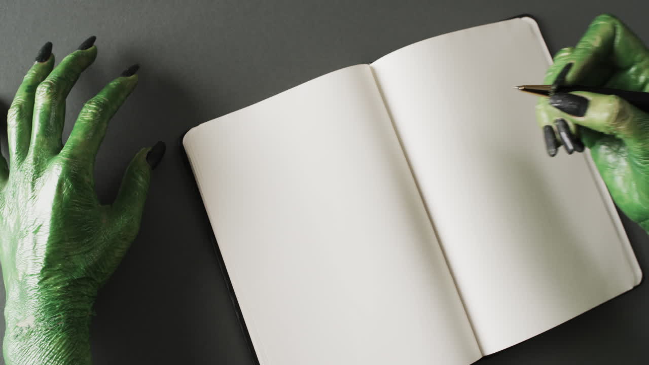 Video of halloween green monster hands and notebook with copy space on grey background