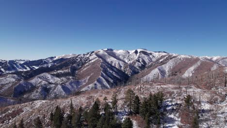 Drone-shot-pushing-forward-and-revealing-a-huge-mountain-range-with-trees