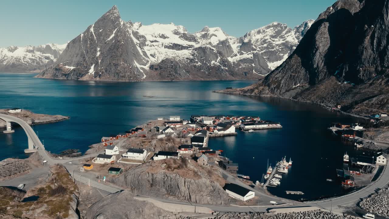 Rocky Mountain Partly Covered With Snow Seen From Reine Fishing Village In Norway. - aerial shot