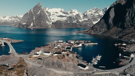 rocky mountain partly covered with snow seen from reine fishing village in norway. - aerial shot