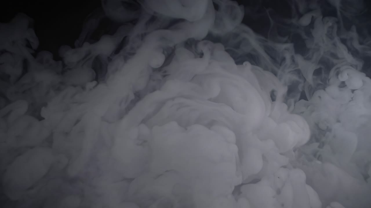 A mesmerizing video captures swirling white smoke against a dark background, shot from a low angle