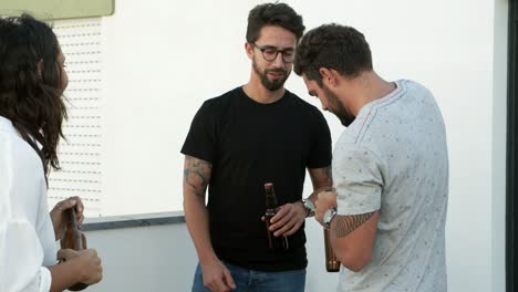 Handsome-young-man-opening-beer-bottles-for-friends