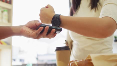 Video-of-hands-of-biracial-woman-paying-with-smartwatch-for-coffee