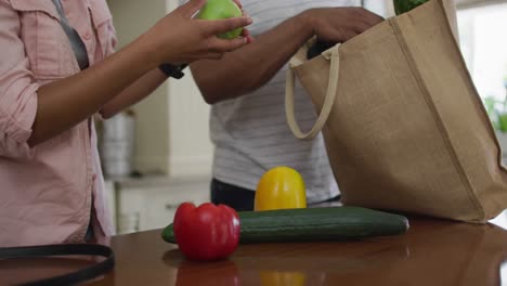 Hands-of-biracial-couple-unpacking-groceries-in-kitchen