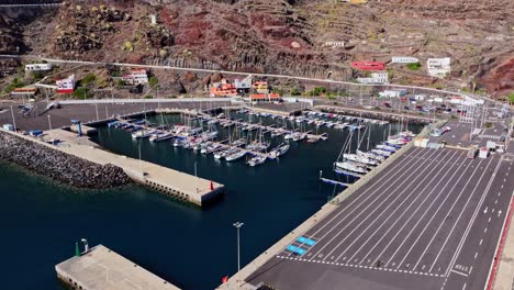establishing aerial of puerto de la estaca harbor with boats and rocky coastline