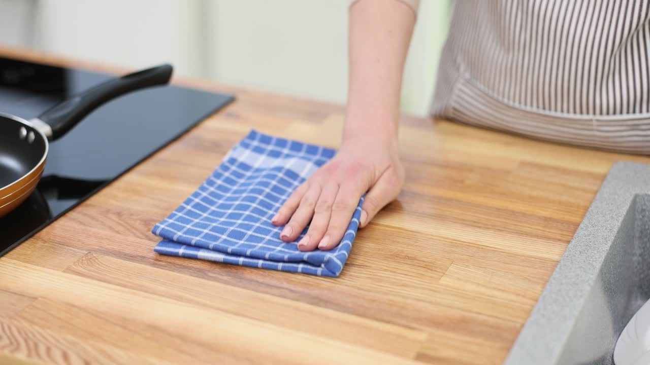 A person wiping a kitchen countertop