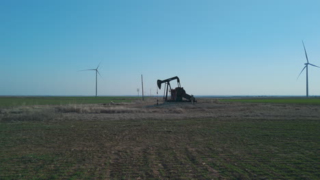 oklahoma - oil pumpjack with wind turbines in background wide shot