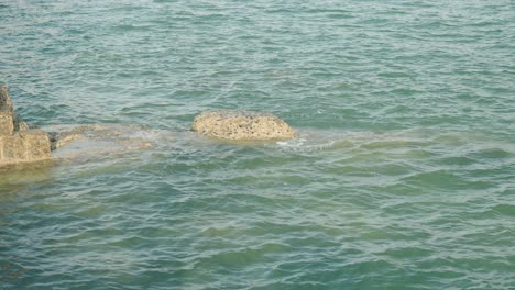 Nahaufnahme-Einer-Felsigen-Halbinsel-An-Der-Küste-Von-Seaford,-Die-Von-Wellen-Getroffen-Und-Von-Der-Untergehenden-Sonne-Wunderschön-Beleuchtet-Wird