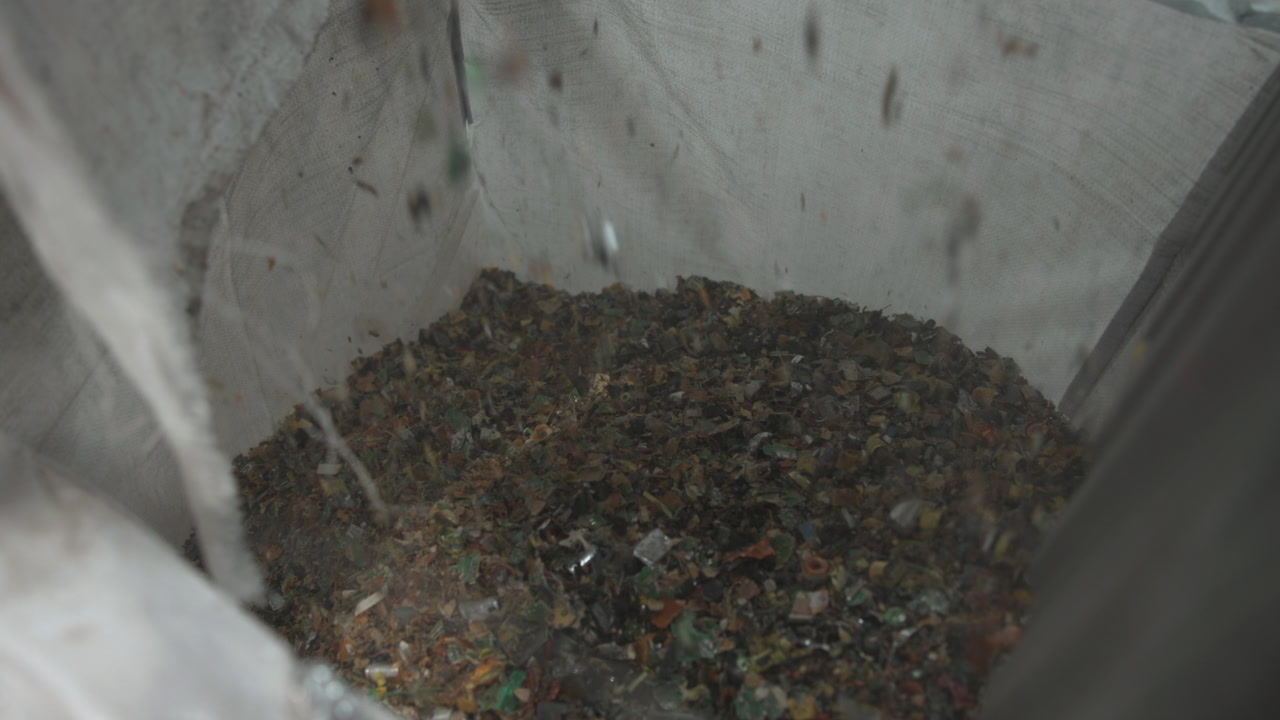 Closeup Plastic Flakes In Bulk Bag, Industrial Recycling Facility Interior With Gray Woven Fabric Sack Holding . Media