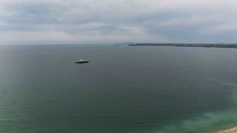 Ship-On-The-Ocean-Against-Cloudy-Sky-In-St-Ives,-Cornwall,-England---aerial-drone-shot