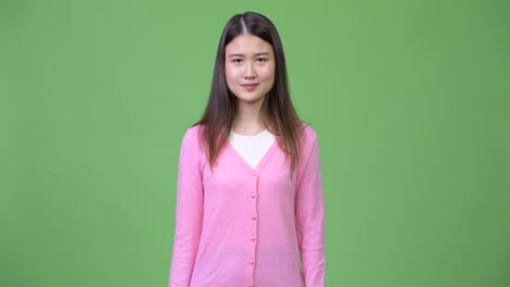 young beautiful asian woman shrugging shoulders