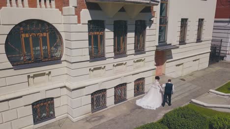 bride and groom walk to beautiful building steps aerial view