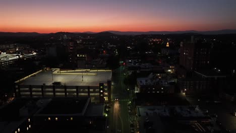 driving cars on main street of small town in america. lighting car park in downtown with golden sunset in background. aerial descend wide shot.