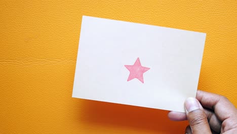 hand holding a card with a red star