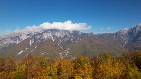 Golden-foliage-of-trees-and-the-Alps-mountain-background,-clouds-and-blue-sky