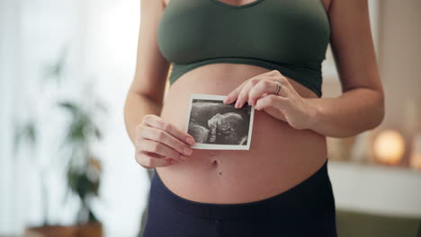 pregnant woman holding ultrasound of her baby