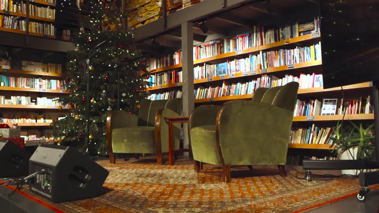 уютная обстановка и сцена в библиотеке или книжном магазине в таллинне, называемом "читайте", где есть сцена с диванами и сиденьями перед хорошо освещенными книжками, которые заполнены старинными книгами.