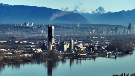 industrial cement factory with chimney pipes emitting smoke in british columbia, canada. aerial shot