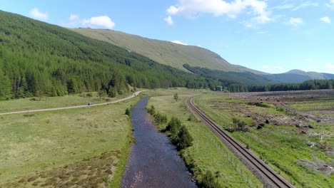 low tracking shot through glen lochy above the river and between the road and the railway