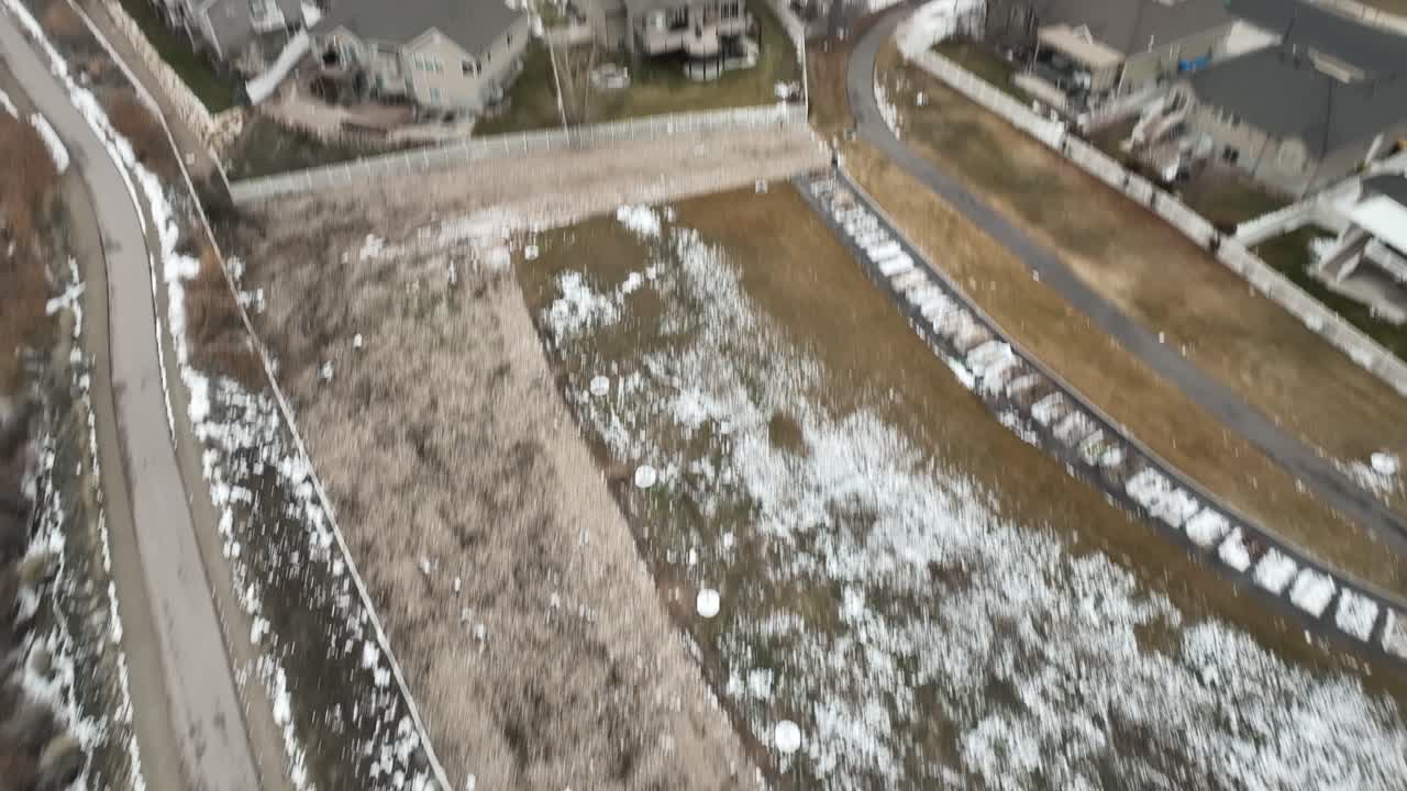 Straight down aerial view of the Jordan River Parkway trail then tilt up to reveal the suburb of Cranberry Farms in Lehi, Utah