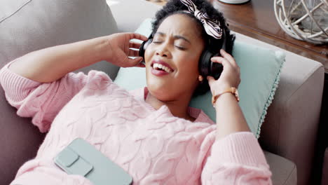 african american woman enjoys music on a couch at home