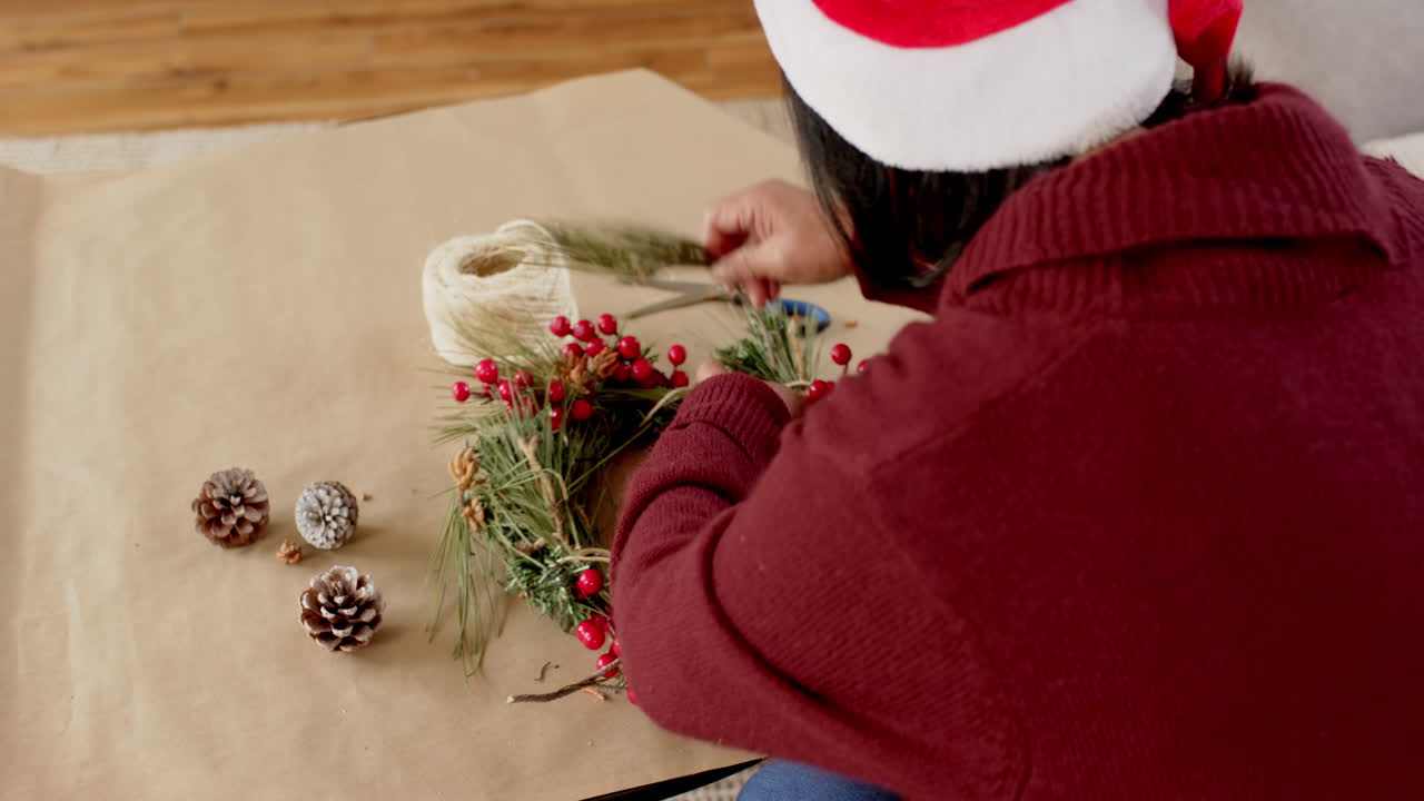 Christmas time, Crafting festive wreath at home, person wearing Santa hat and red sweater