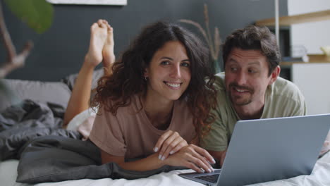 pareja trabajando en la computadora portátil en la cama