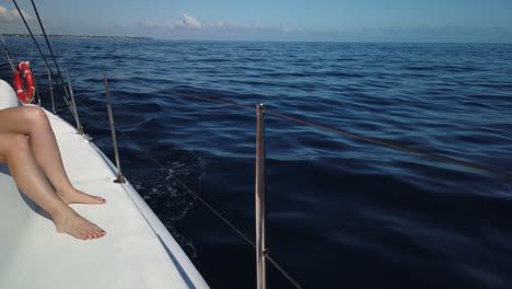 una toma desde el lado de babor de un catamarán del mar, con las piernas de una mujer a la izquierda de la toma