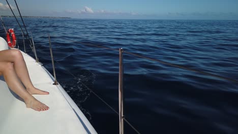 a shot from a catamaran´s port side of the sea, with a woman´s legs at the left of the shot