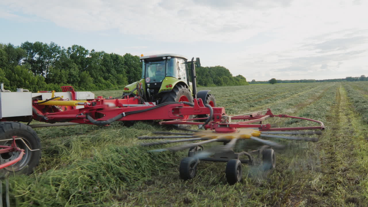 tractor trabajando en el campo recogiendo en una fila hierba verde