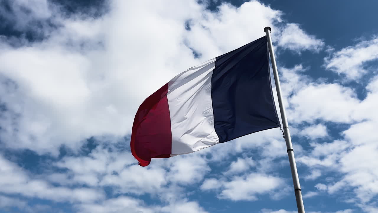 A flag of France flying in the must with the blue sky