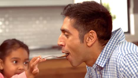 Smiling-Hispanic-father-is-fed-by-his-daughter