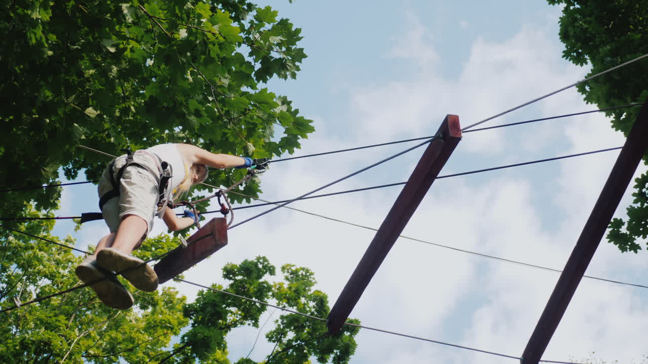 용감한 아이가 키 큰 나무 사이의 줄타기를 따라 걷는다 활동적인 어린 시절과 재미