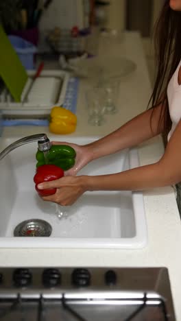 woman washing vegetables in kitchen sink