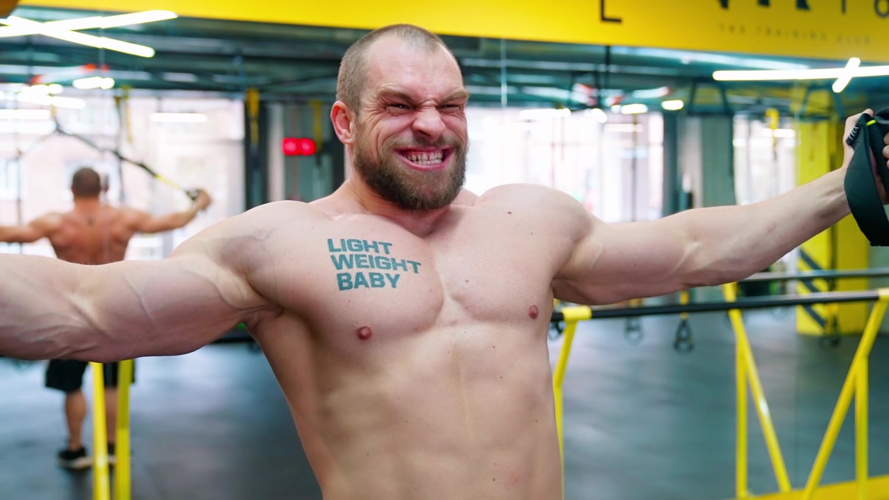 Uomo muscoloso che esegue allenamento in sospensione TRX in una palestra moderna