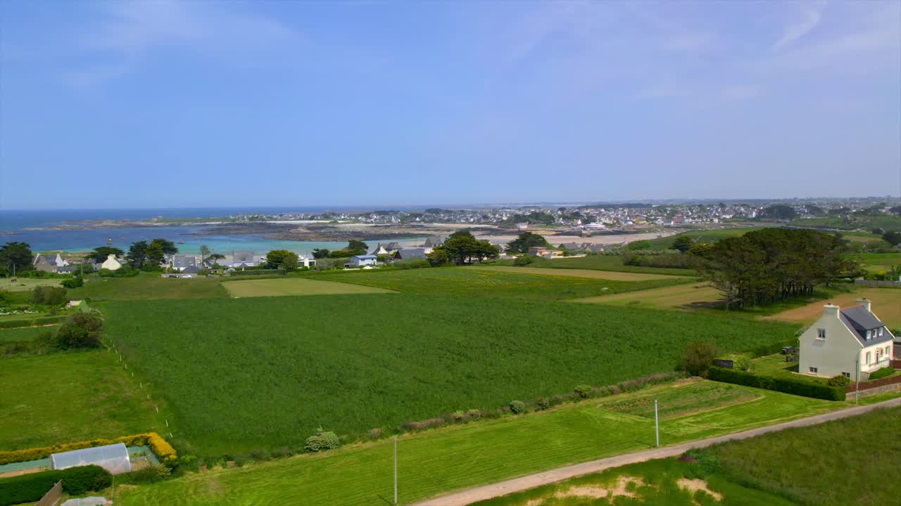 Drone footage captures a green farmland leading to a coastal village and ocean views in Brittany, France. This scenic landscape combines rural charm with seaside beauty, ideal for travel and nature.