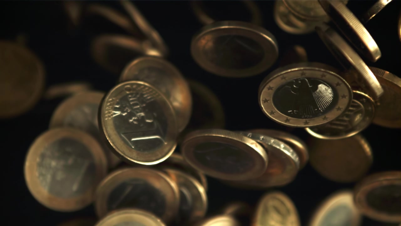 Golden Euro Coins Falling into Focus in Slow Motion