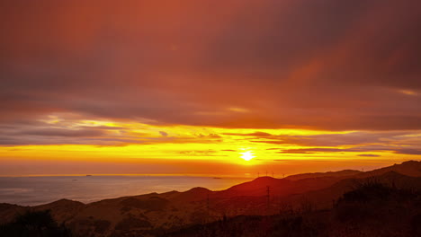 Una-Vista-Del-Atardecer-En-El-Mar-Con-Un-Colorido-Paisaje-De-Nubes-Y-Una-Silueta-De-Montaña-En-España