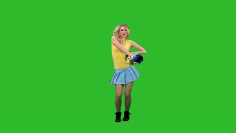 a cheerleader vigorously moves her hips, pom-pom arms, whirls and waves her hair. a girl with a yellow-blue uniform is dancing a jubilant dance in the studio on a green screen. slow motion