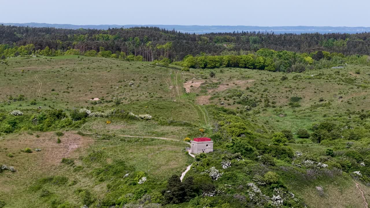 Drone footage shows an old German World War II bunker surrounded by overgrown brush and forest edge